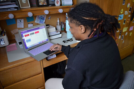 A female student works on a laptop in a dorm room