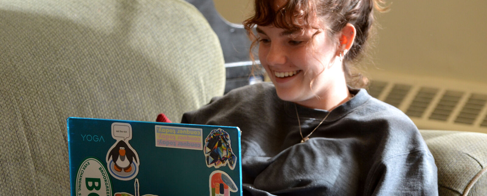 A female student works on a laptop in a student lounge.