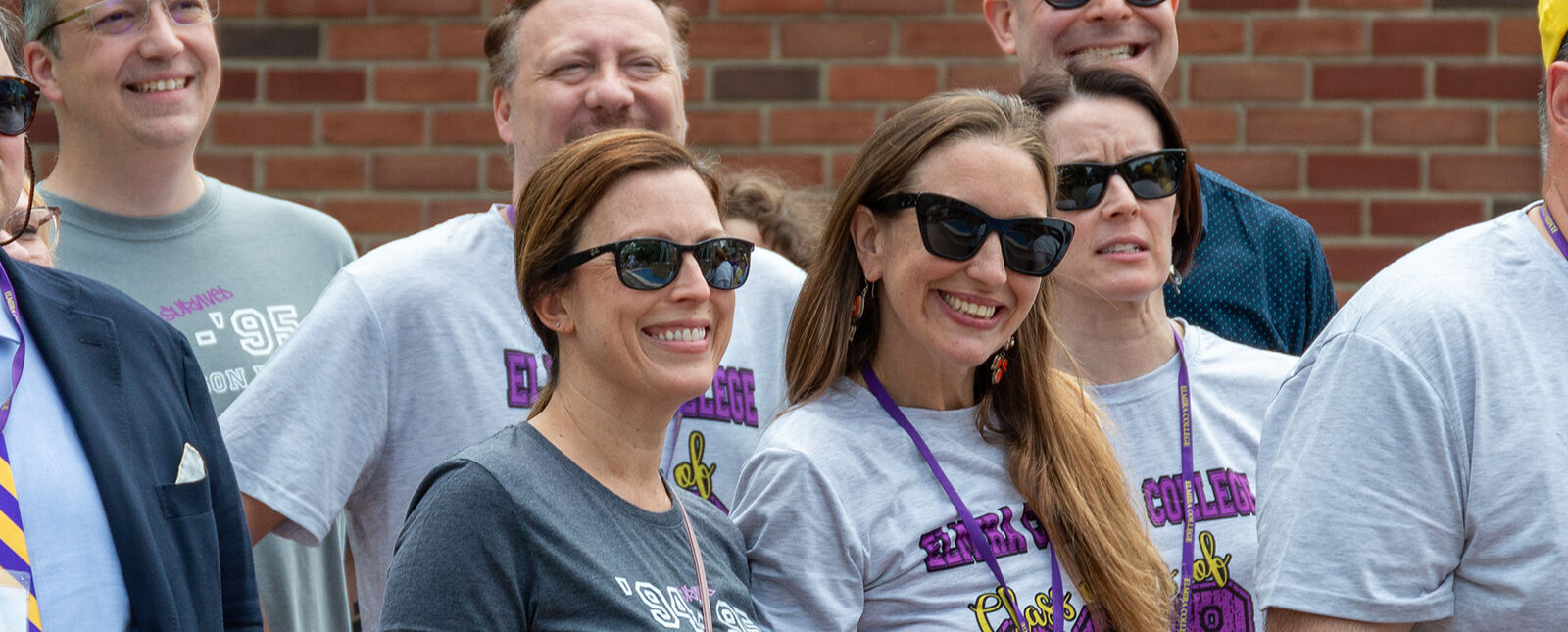 Two female alumni smile among a group of fellow alumni
