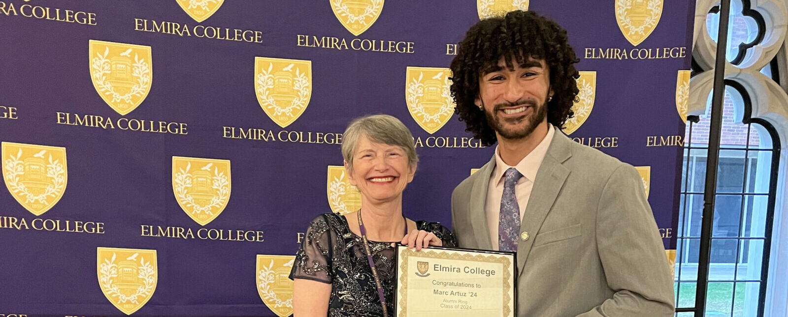 A male student receives his alumni ring from a female alumni