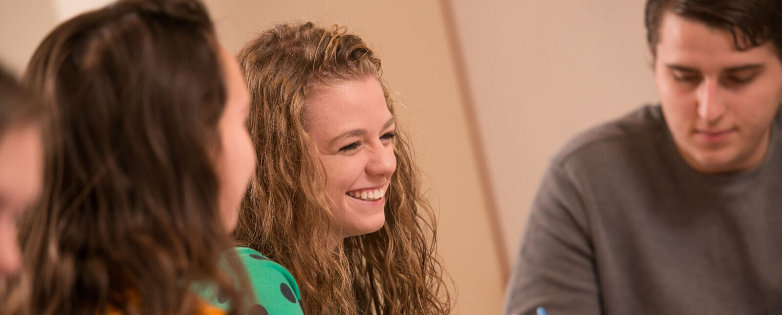 A female student smiles while working on a class assignment with a group
