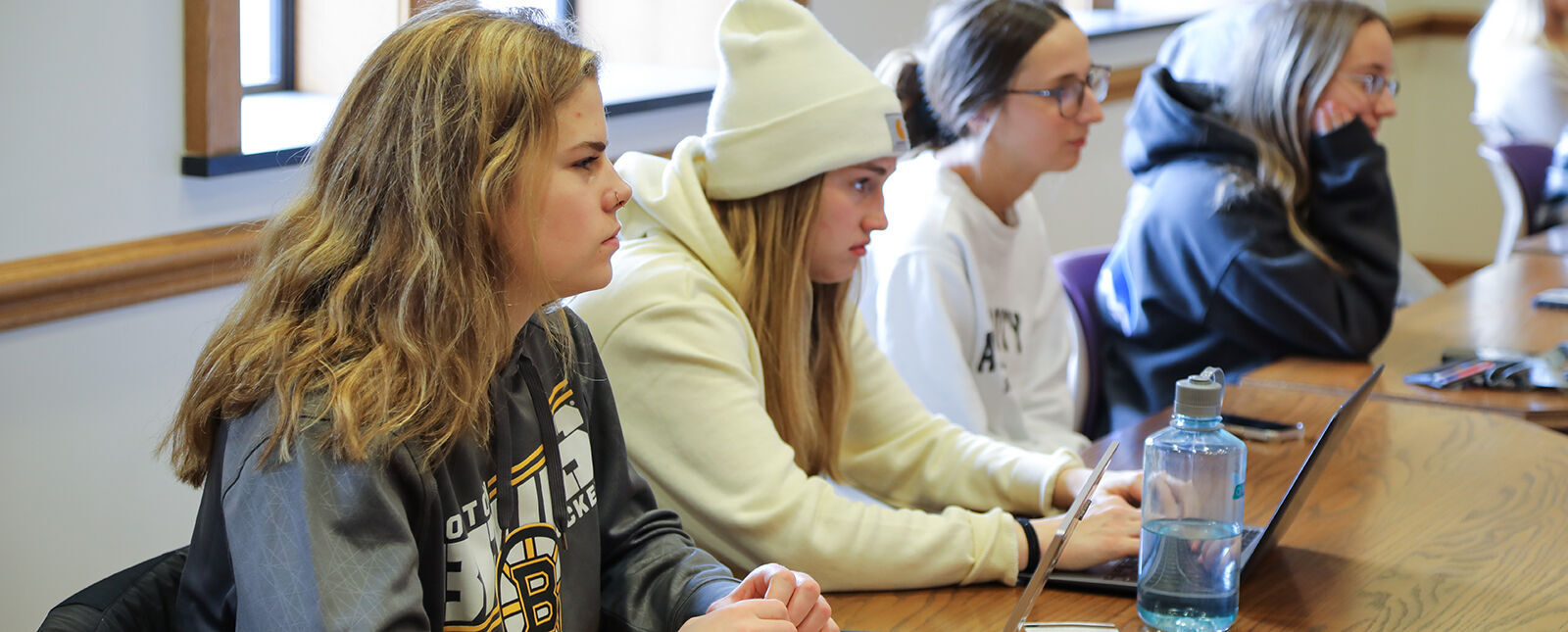 Students sit at a table listening and taking notes during the Climate Teach-In