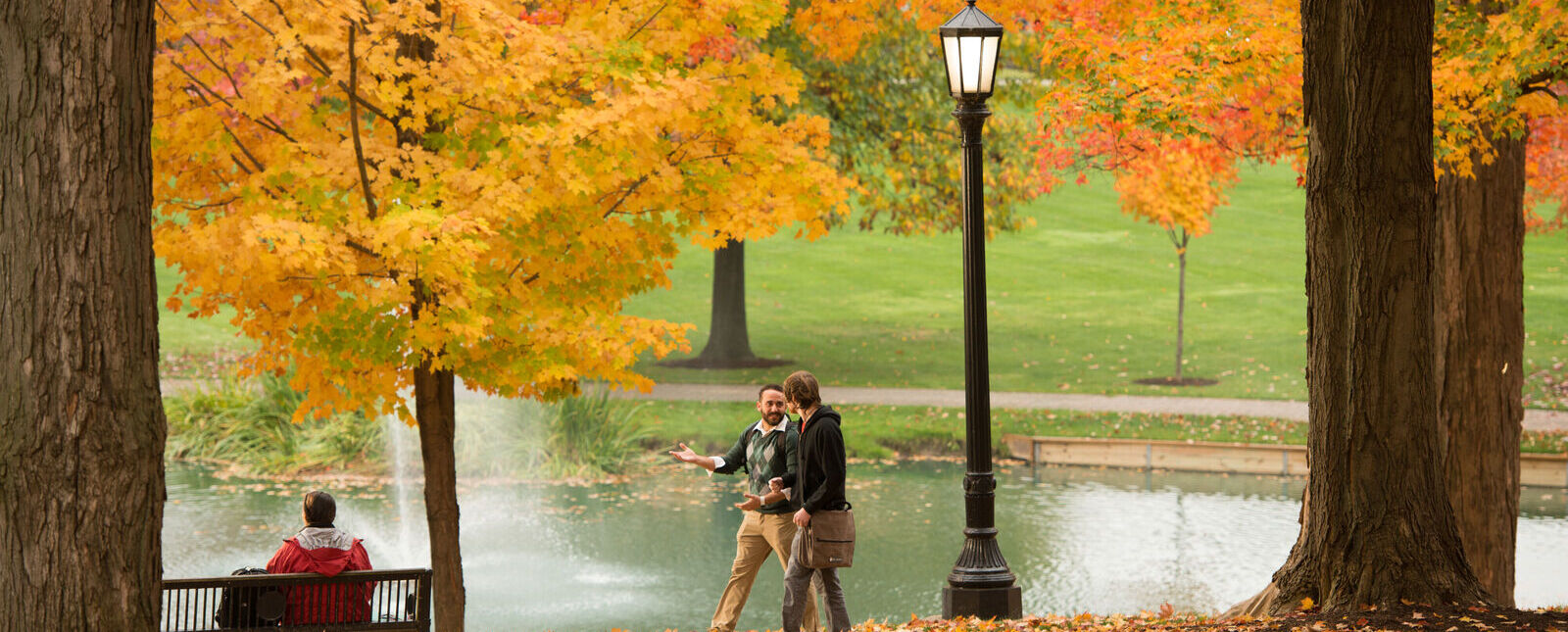 Two men walk during autumn with the Puddle in the background. 