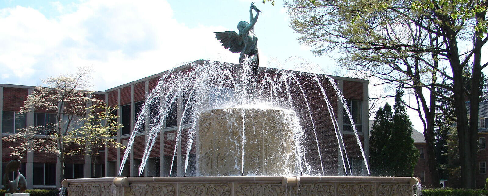 Multiple streams of water shoot out of the fountain in front of McGraw Hall