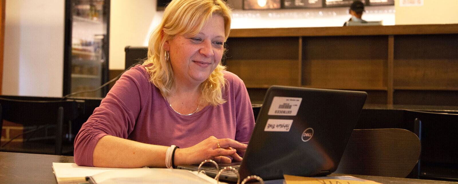 A graduate student works on a laptop in a cafe