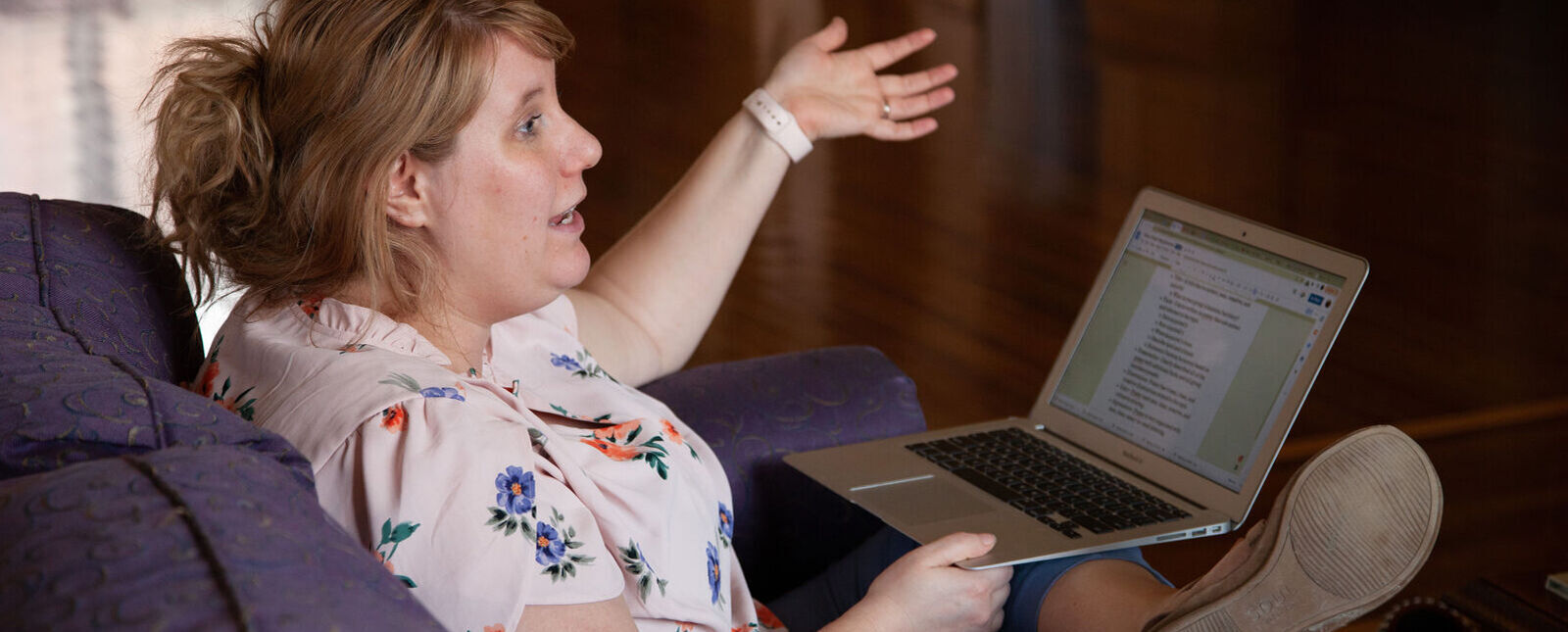 A female graduate student talks while sitting with a laptop in Stephans Lounge 