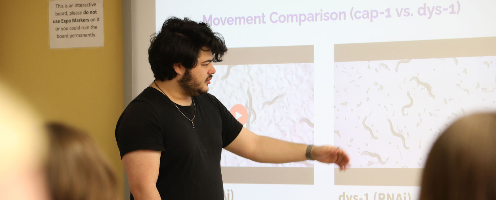 A male student presents scientific research to the classroom