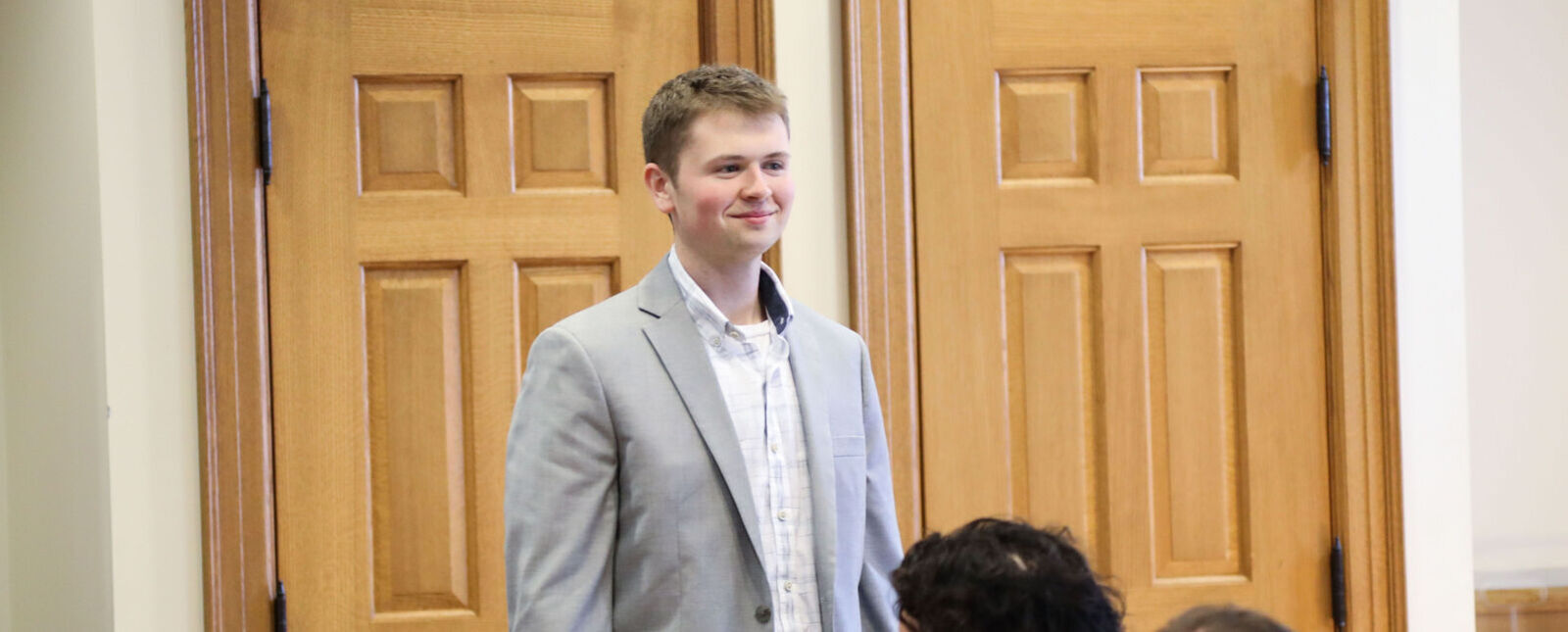 A male student stands up during the Sigma Beta Delta induction ceremony