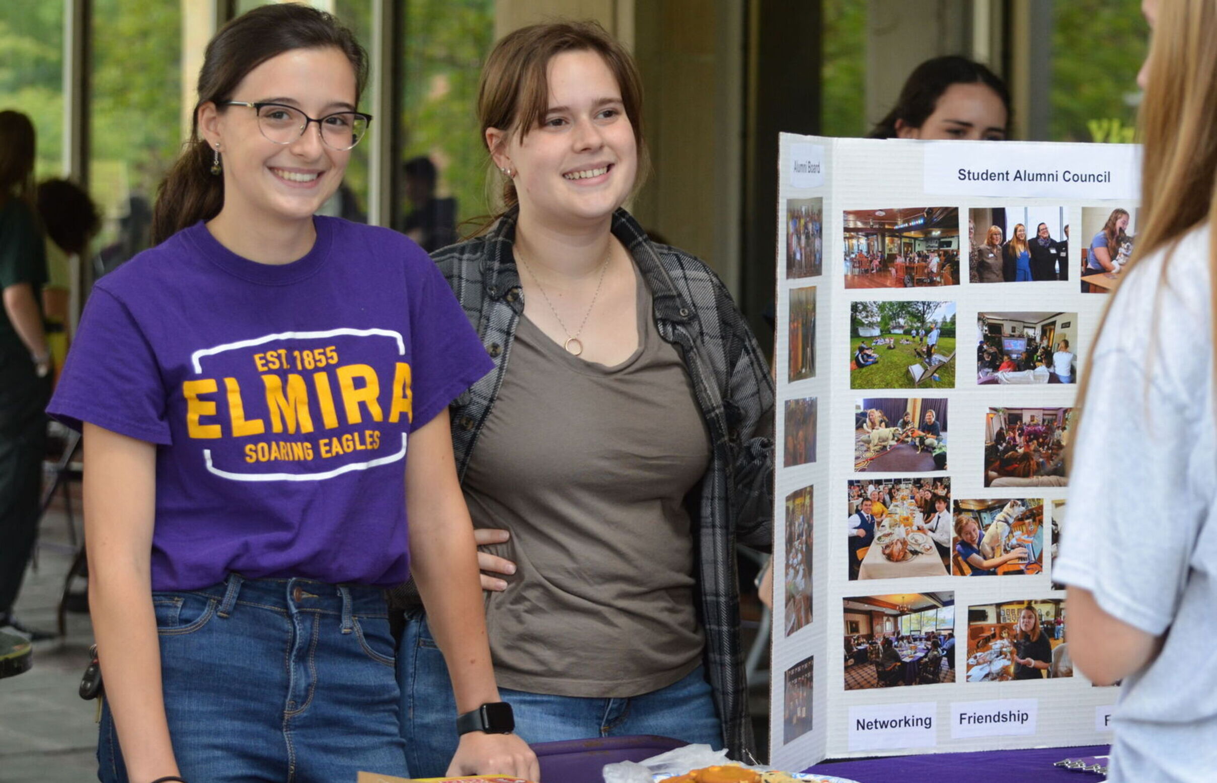 Two female students greet guests at the Student Alumni Council table