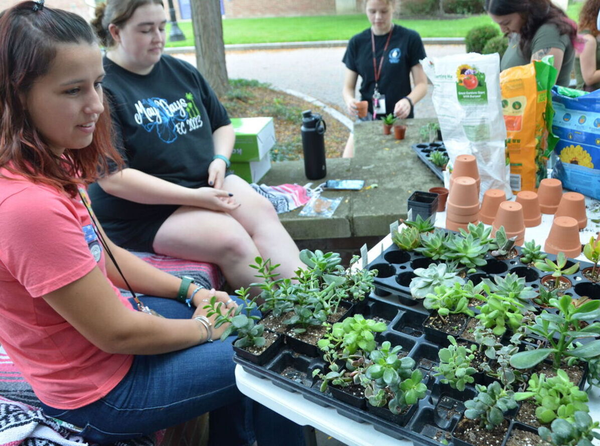 Students sit around plants at the Environmental Club table