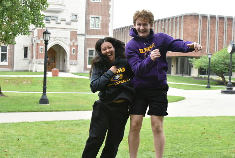 A female and male student jump into a shoulder bump in celebration during the Lawnsay Games