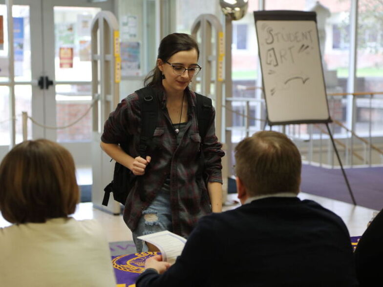 A student stops by a table during the Life After EC event in the Gannett-Tripp Library