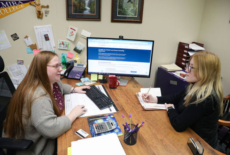 A female financial aid counselor helps a female student in her office