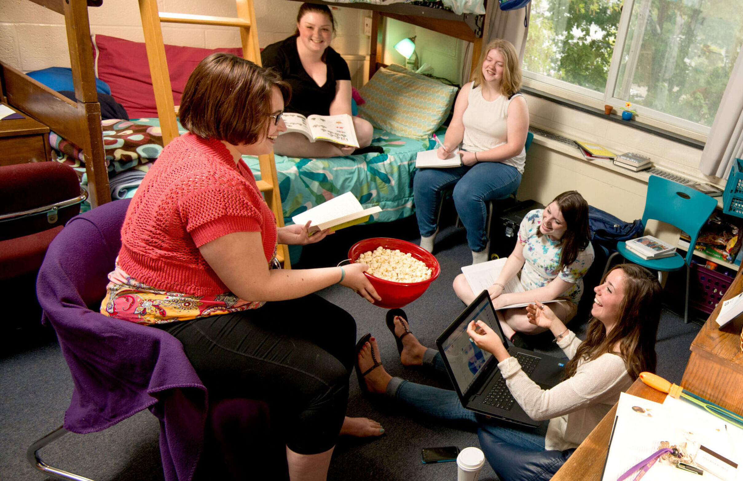 A group of female students hang out and enjoy some popcorn in an Anderson Hall dorm room