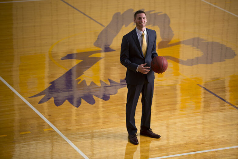 A man in a suit stands in the center of the basketball court