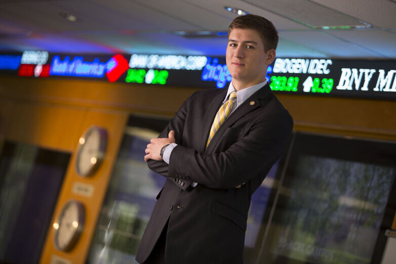 A student in a suit poses in the finance trading room