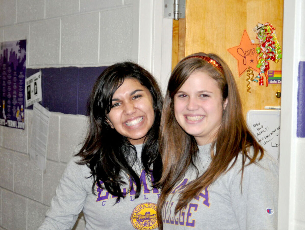Two female roommates smile outside of their dorm room in Columbia Hall