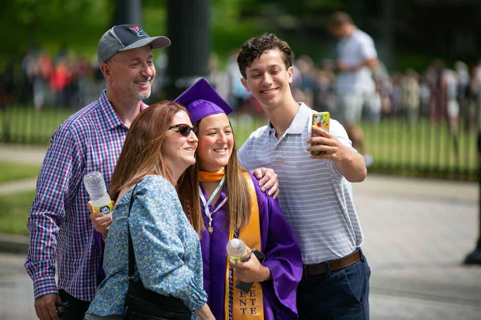 A family poses for a selfie with their graduate