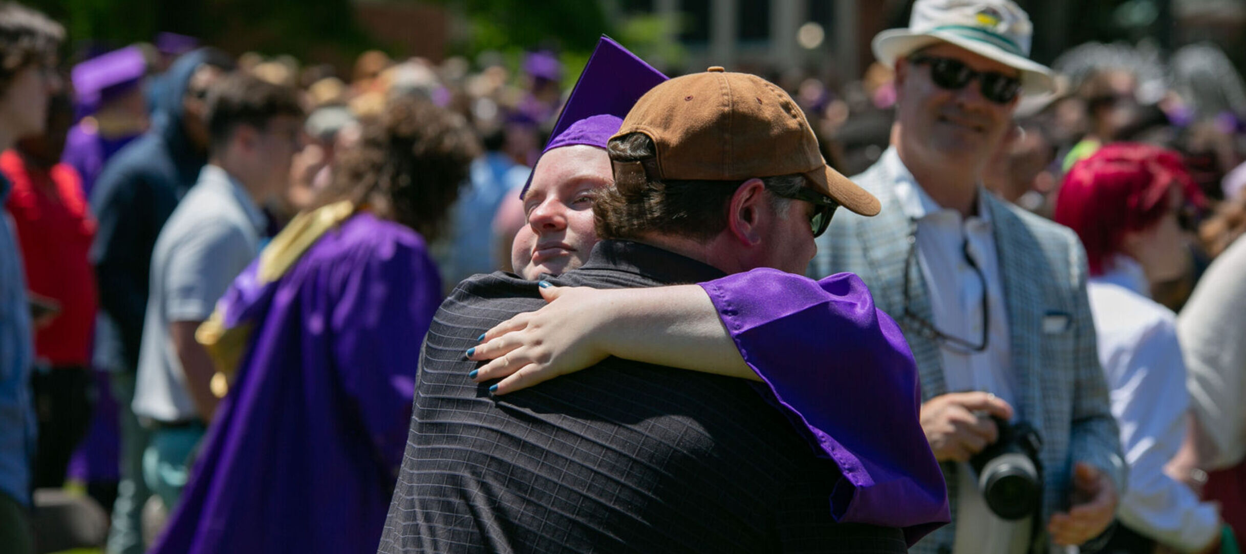 A graduate hugs a family member after commencement