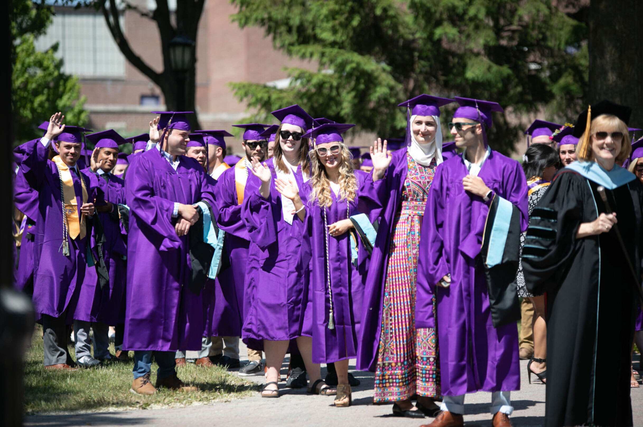 A group of Class of 2023 graduates wave at the camera during Commencement
