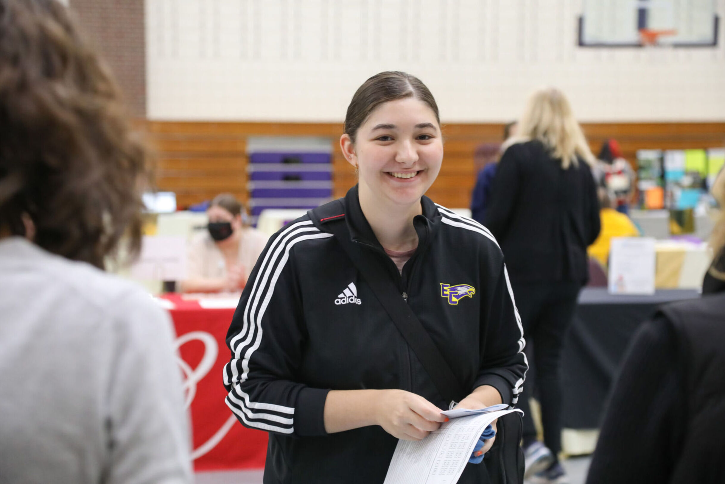 A female student smiles while visiting a booth at the Community Engagement Fair