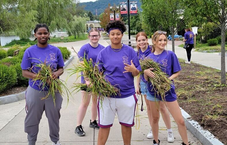 Students pose with weeds they pulled as part of their community service at Eldridge Park.