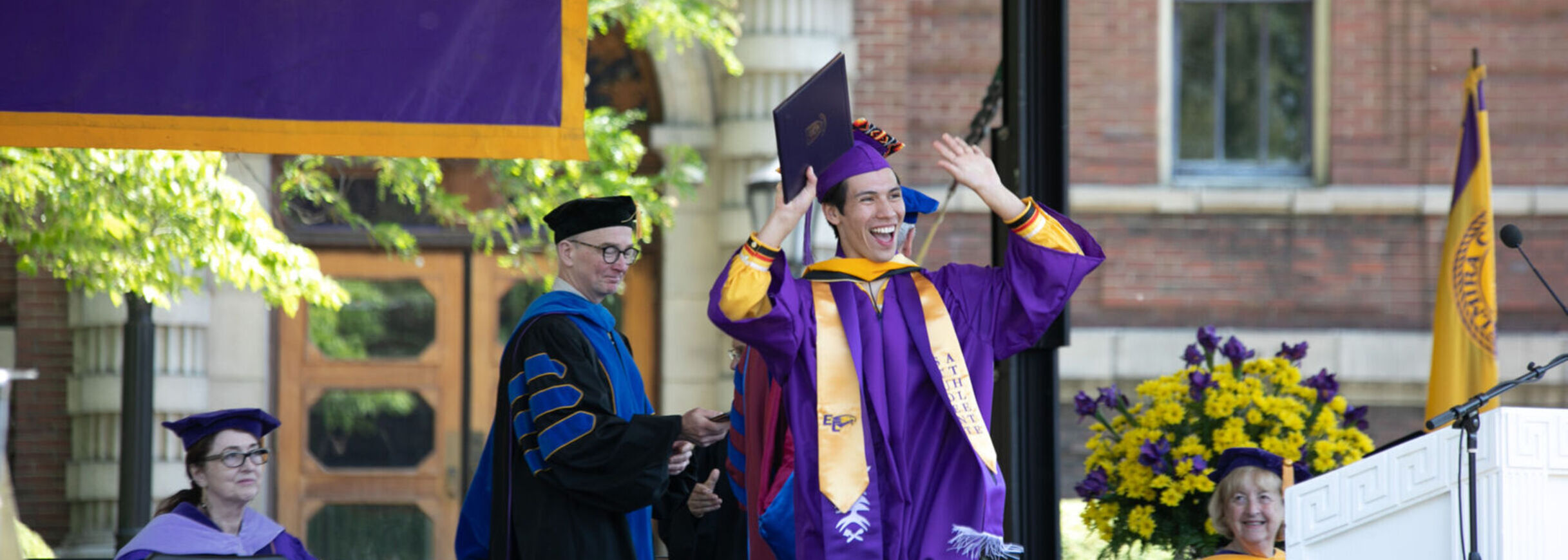 A graduate waves to the crowd after receiving his diploma