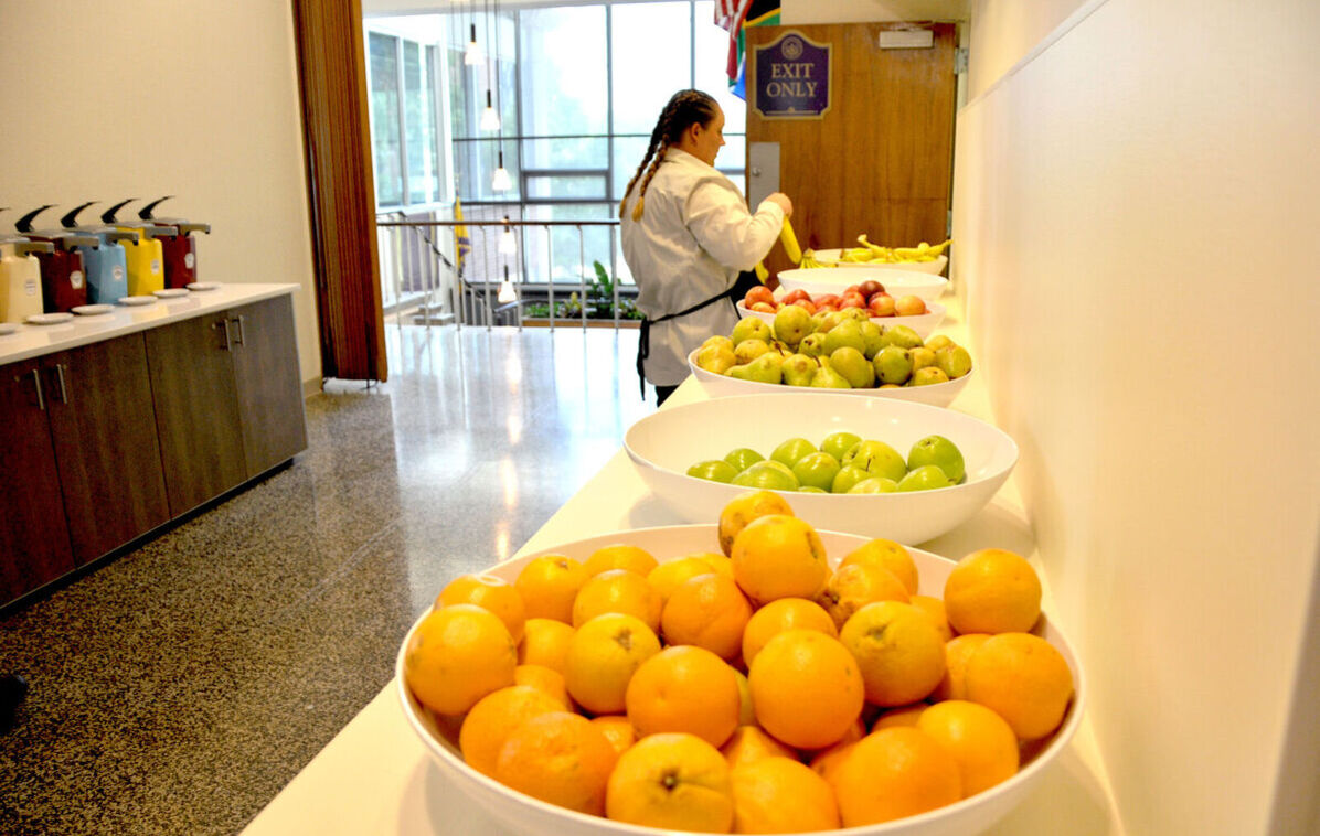 A dining hall worker prepares bowls of fruit