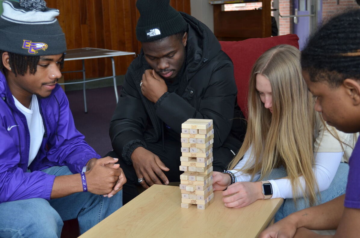 Four students play Jenga in a residence hall lounge