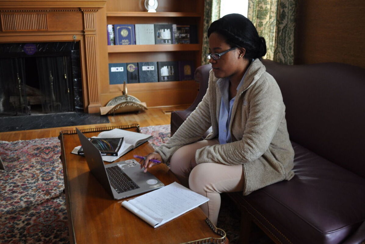 A female graduate student works on a laptop in a lounge area