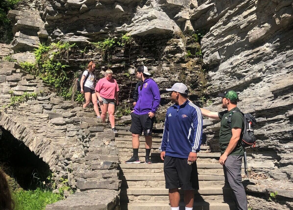 Students walk down stairs along a rocky path in the Finger Lakes area