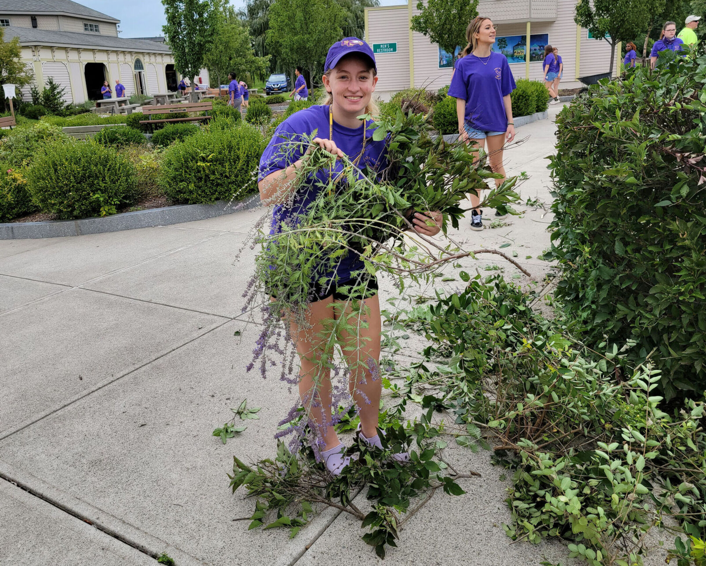 A student holds up a pile of weeds while performing community service at Eldridge Park