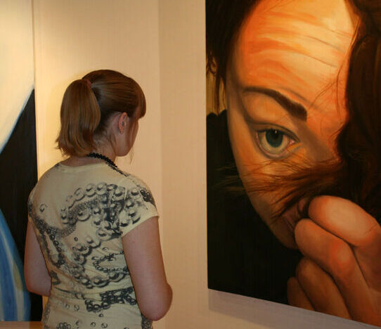 A female student looks at a painting in the George Waters Art Gallery