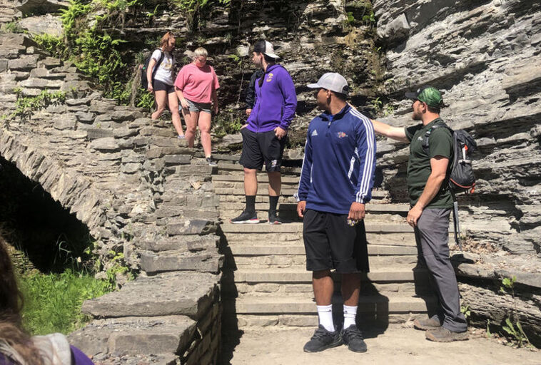 Students hike on a rocky staircase next to a waterfall