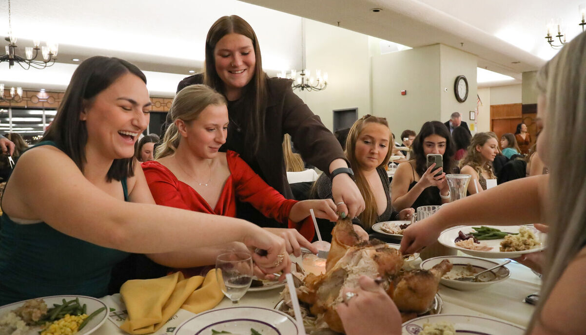 Students share some laughs as they cut into a turkey during the Holiday Banquet