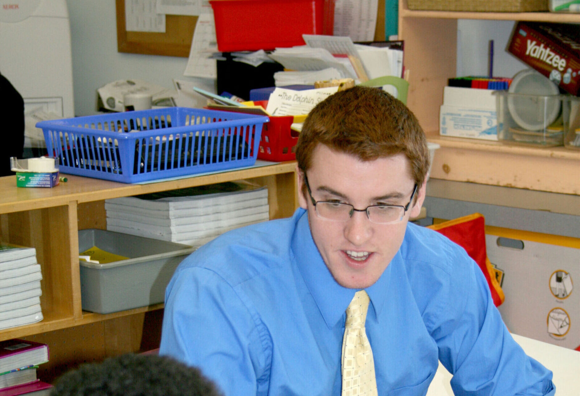 A student teacher works with a student in a classroom