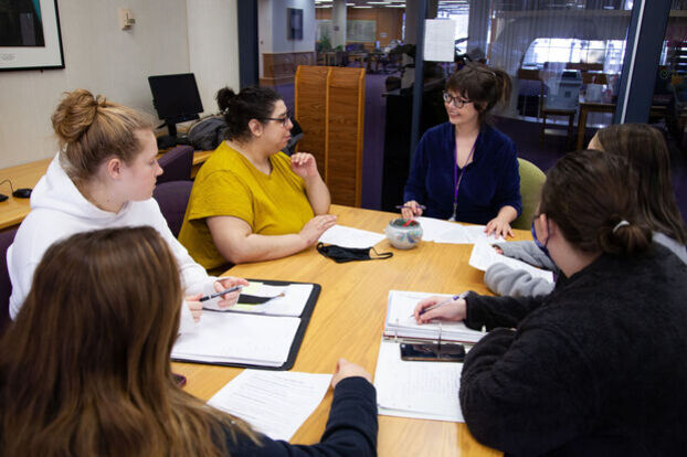 A professor works with a group of students in the Writing Center