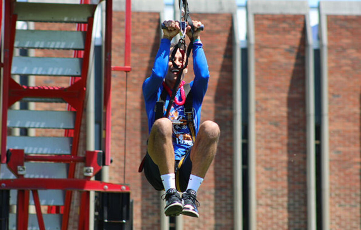 A male student rides the zip line at May Days