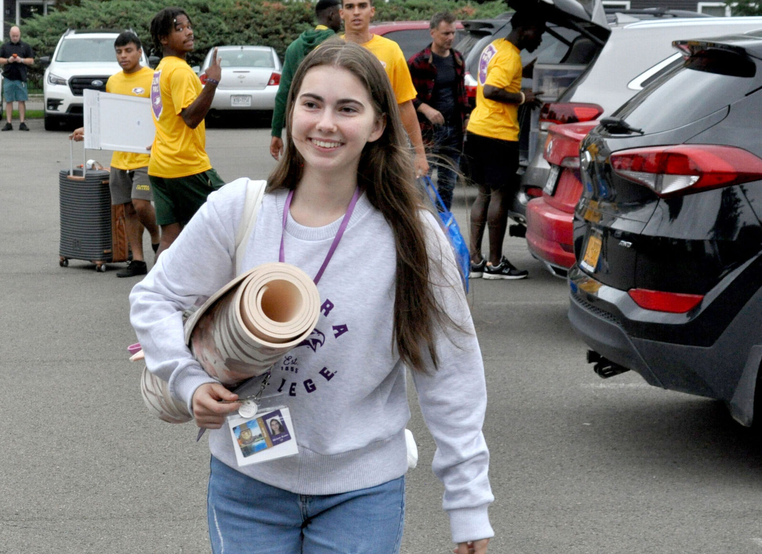 A new female student carries a rug across the parking lot during move-in day