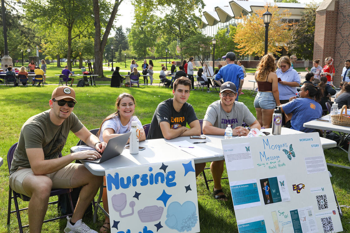 Members of the Nursing Club sit with signs during the Engagement Fair