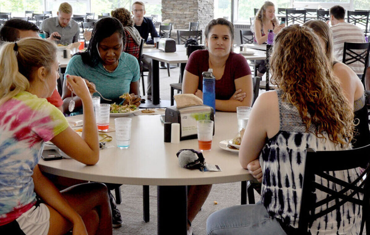 A group of female students talk around a dining hall table