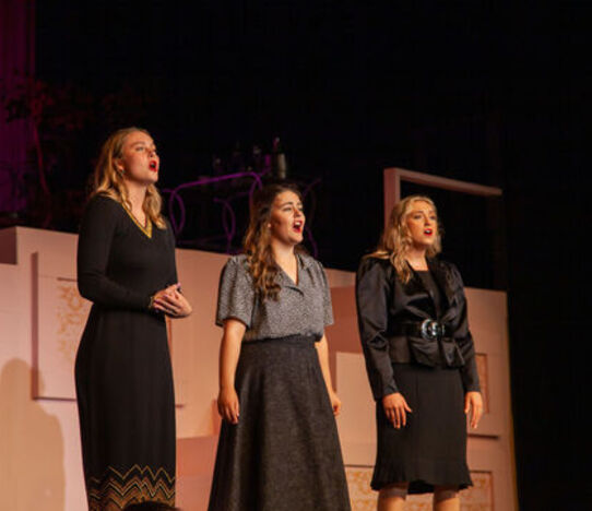Three students sing on the Gibson Theatre stage