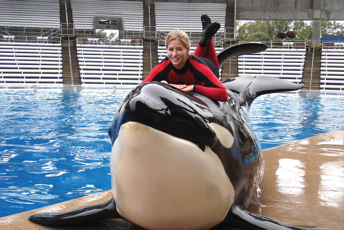 A student lays on top of an orca she worked with as part of an internship