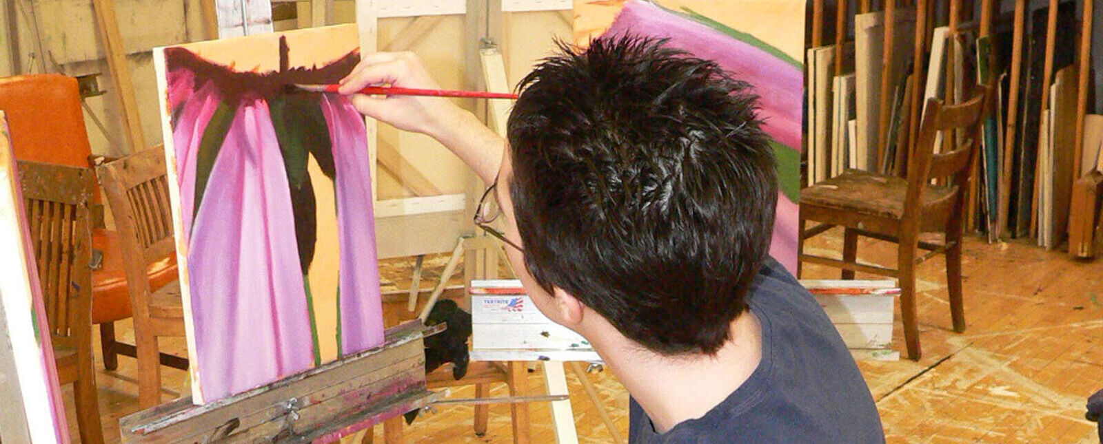 A female student paints on a large canvas
