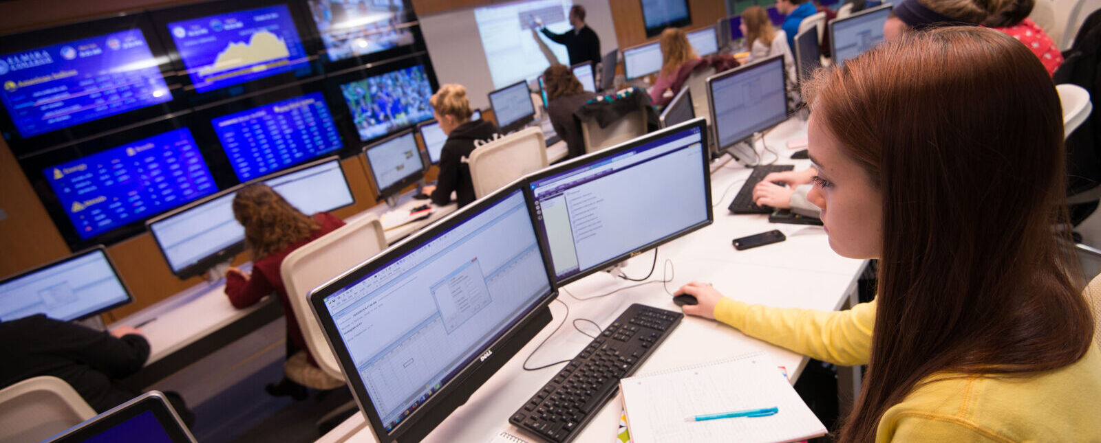 A female student looks at two monitors in the Malesardi Finance Trading Room