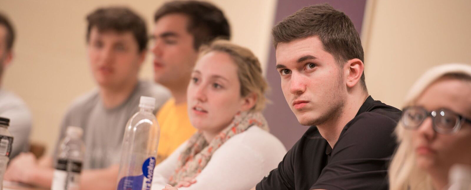 Multiple students listen in class.